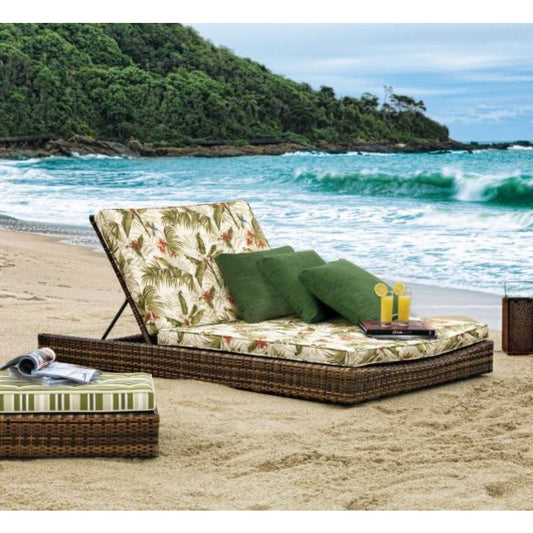 Beachside outdoor lounge with floral cushion and green pillows, set against a scenic ocean backdrop.